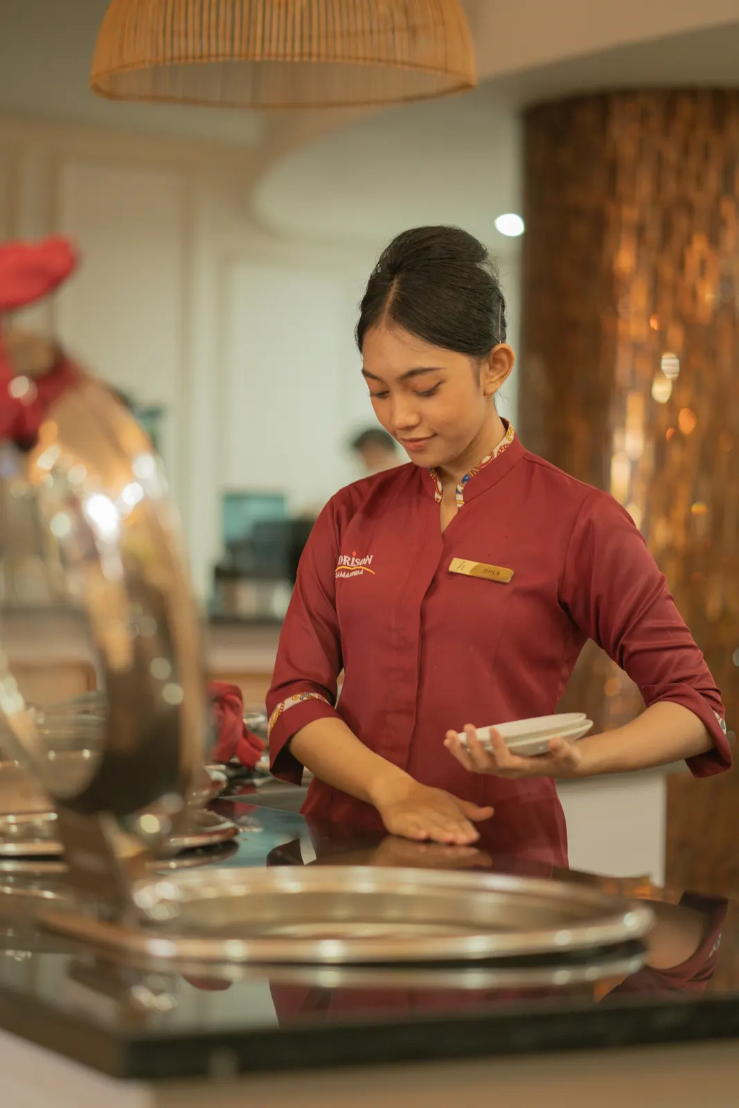 Mesera arreglando platos en un restaurante de hotel